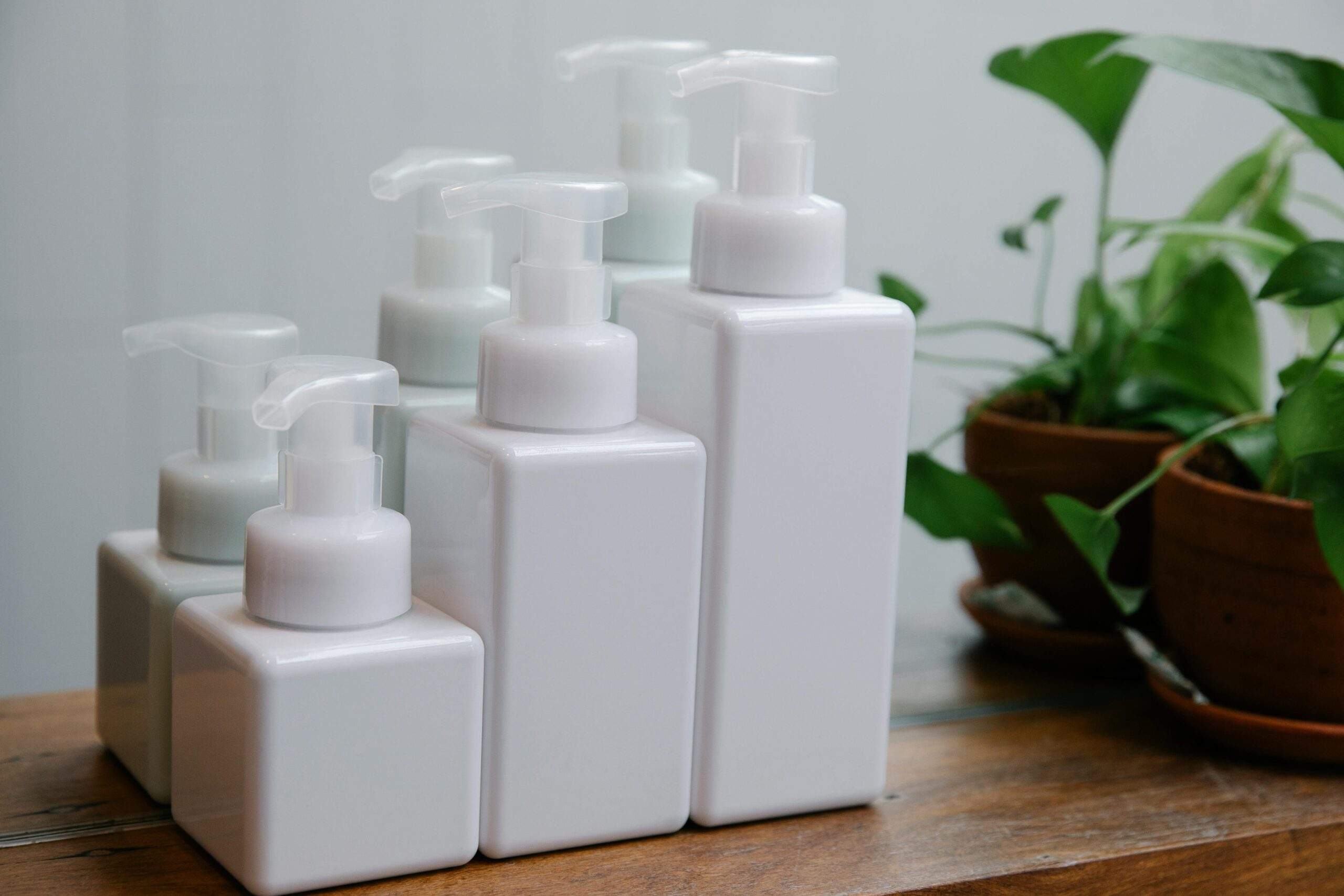 A bathroom counter with skincare products next to small potted houseplants